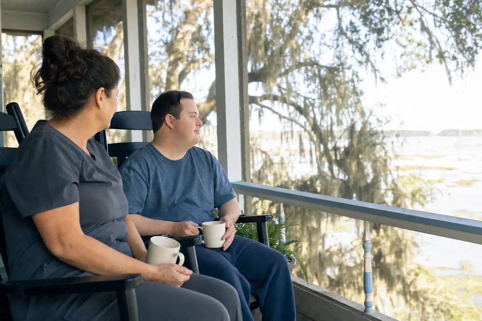 A direct support professional and an adult with a developmental disability on a porch in Louisiana